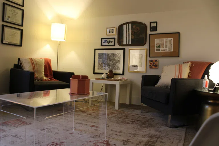 Black chairs around a glass table. Photos on the wall behind.