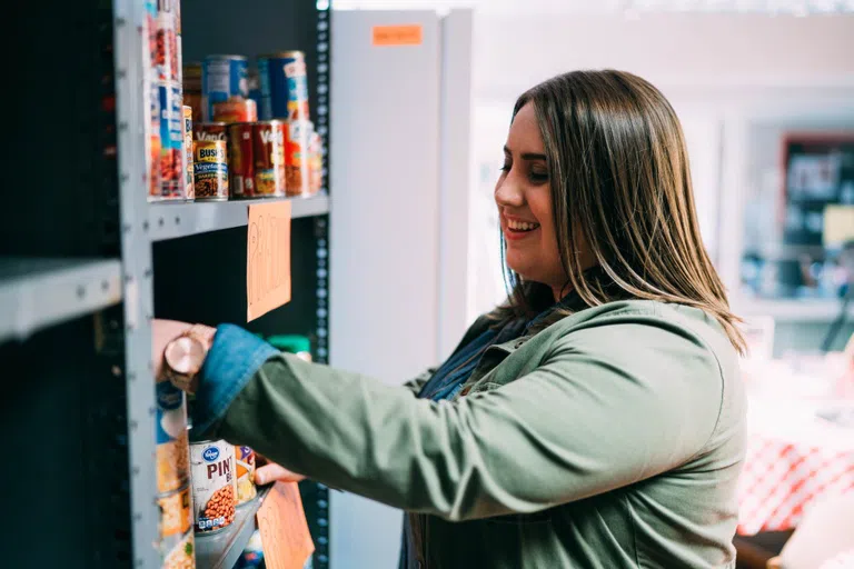 A student volunteer re-stocks a shelf at the Promise House.