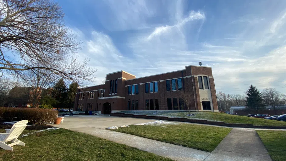 A dark brown brick building against a blue sky with wispy clouds.