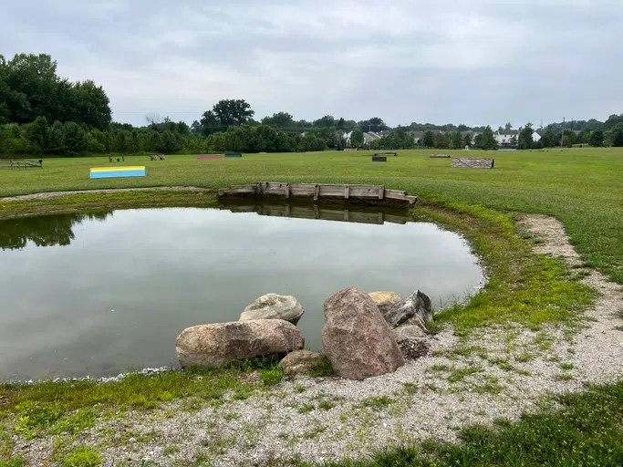 A landscape of a pond with obstacles forming an outdoor horse cross country course.