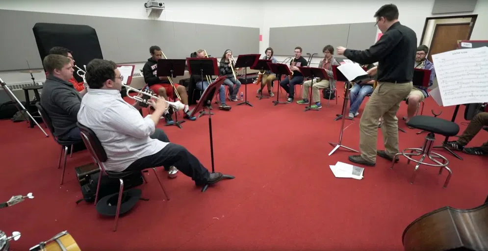 A group ensemble practicing together in a room with a red carpet and white walls.