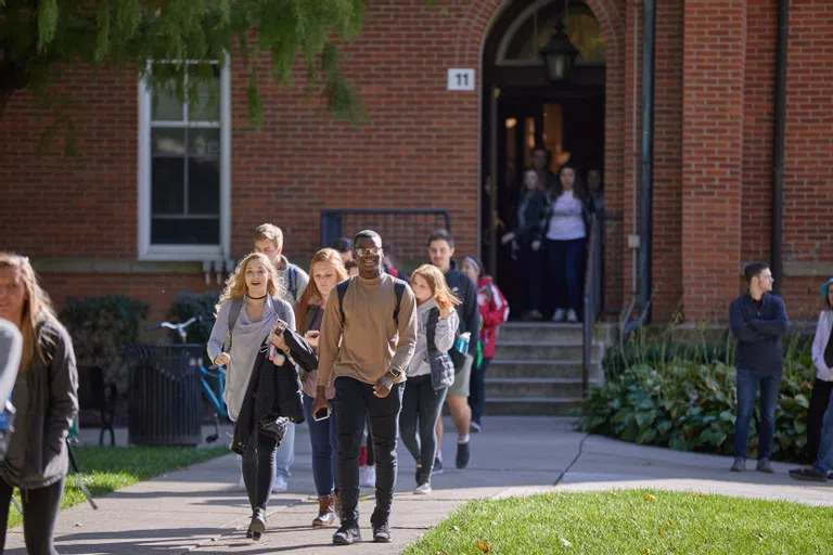 A diverse group of Otterbein students walk out of Towers Hall after classes.