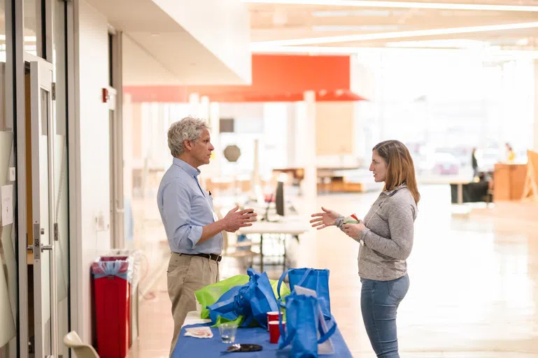 Two people talk at a conference over a booth