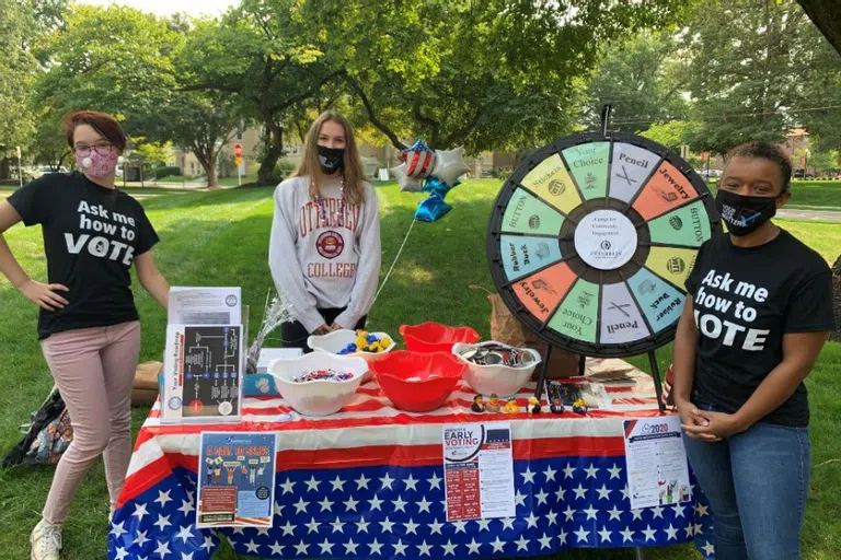 Community Garden volunteers staff a table with free items, information, and games during farmer's market.