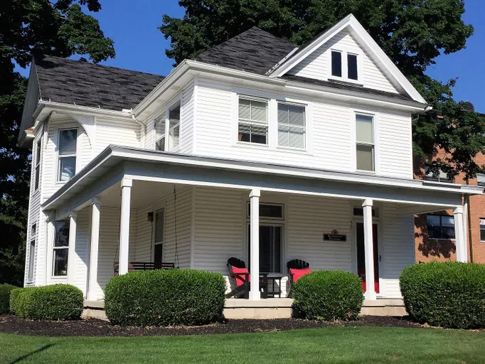 The Psychology House is a three story white house with an inviting and welcoming front porch.