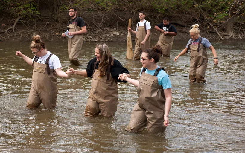 Students knee deep in the water conducting Biology research