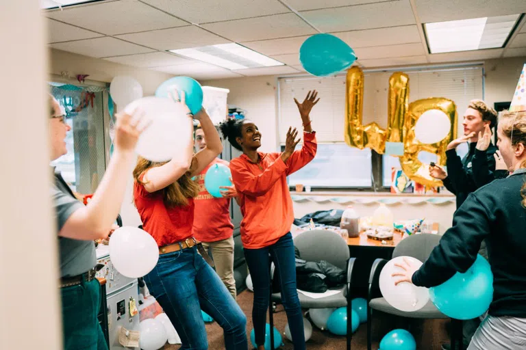 RAs and students have fun with balloons and eat cake at a Res Life party.