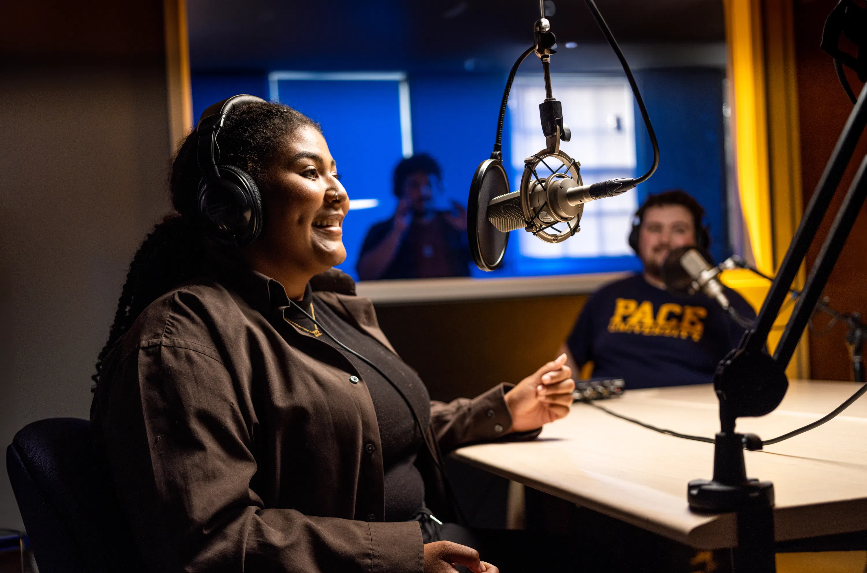 Students in a recording booth speaking into microphones