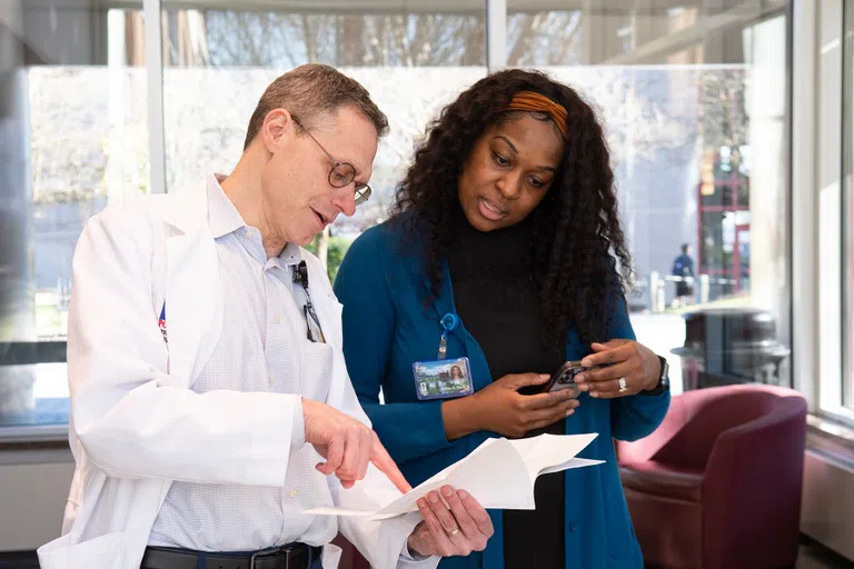 Instructor points out information on a piece of paper to a student. 