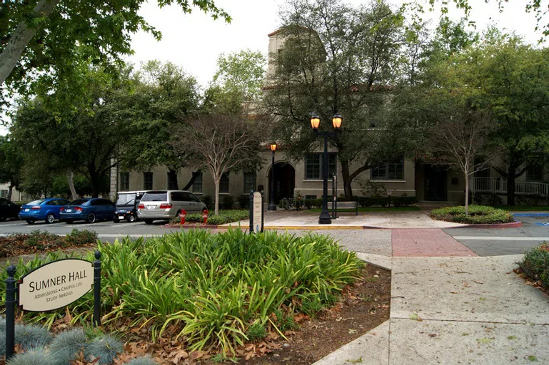 White building with trees and greenery in front