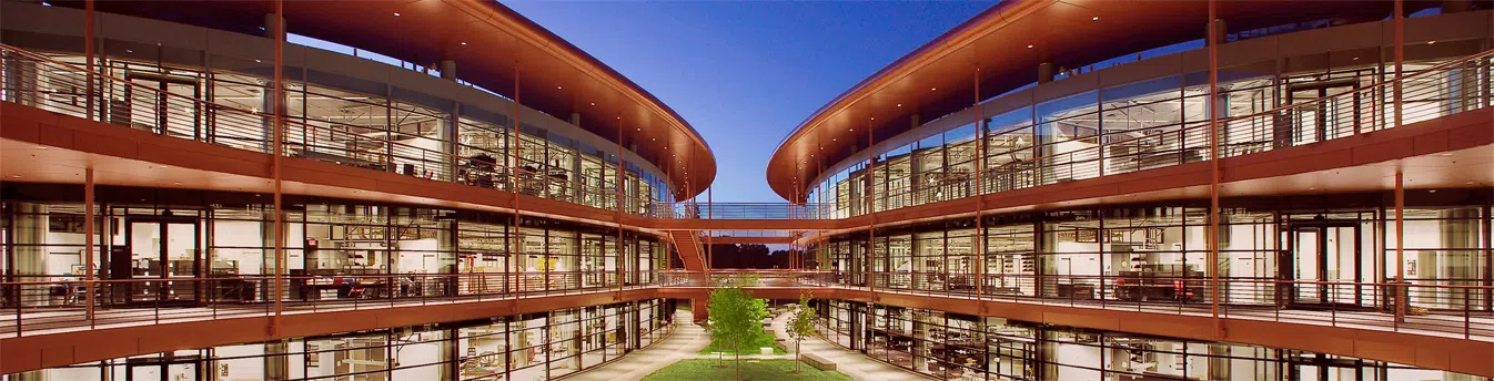 Two modern three-story circular buildings with floor-to-ceiling windows sit next two each other, connected by pedestrian bridges.