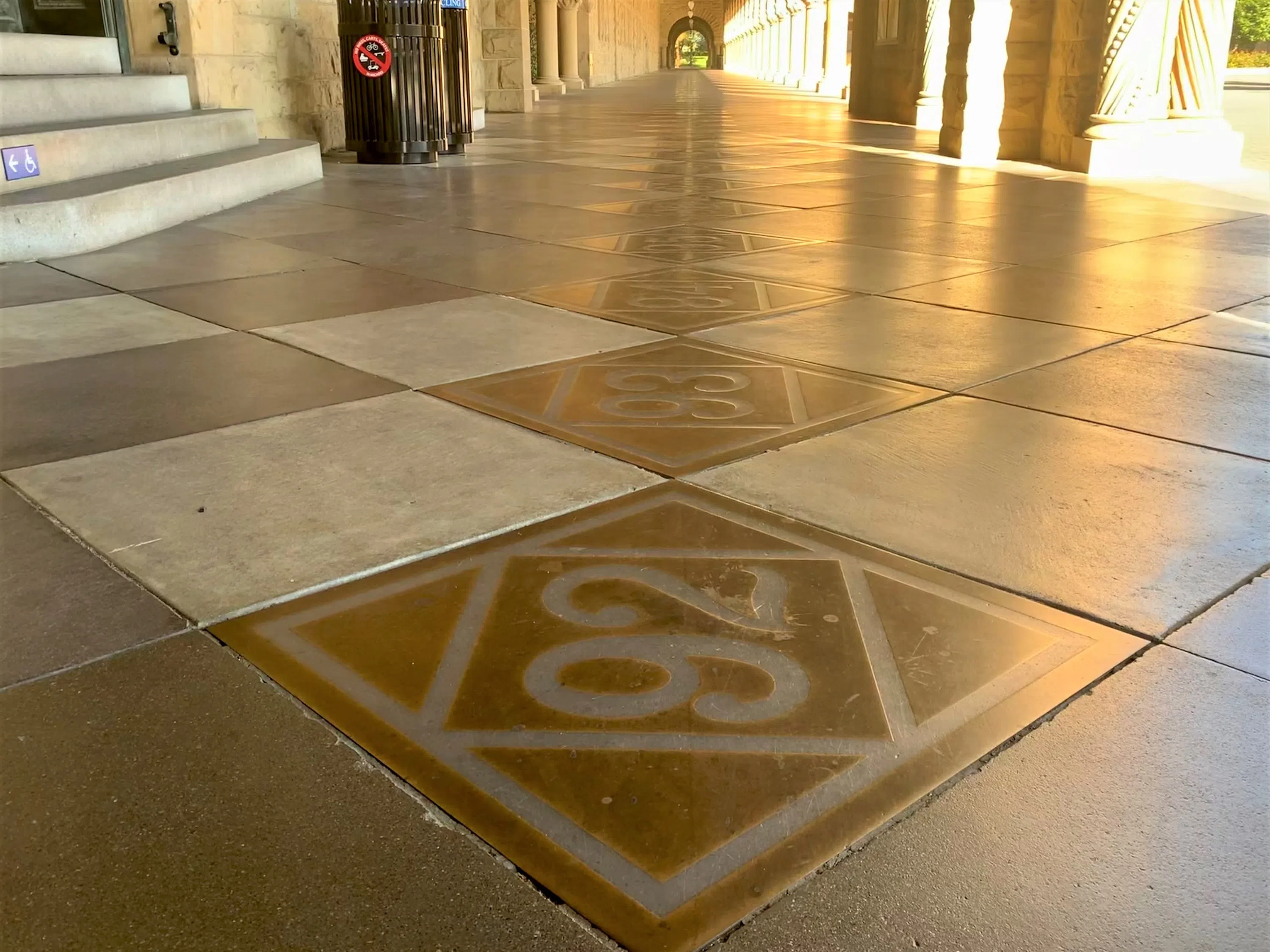 Diamond-shaped brass plates with class years on them line pathways of the arcades of the Main Quad.
