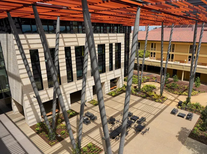 Roof-level view of modern limestone building with multiple diagonal beams supporting an elevated shade lattice