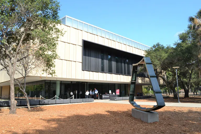 Interior of museum with modern stairwell leading up to second floor gallery displaying modern art paintings