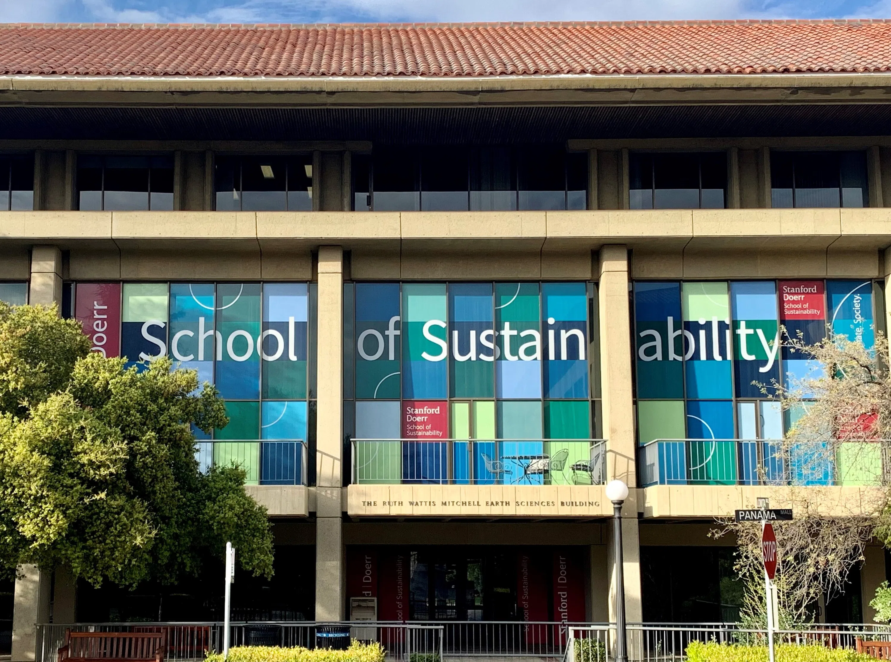 Multi-story building with windows containing colorful signs filling the windows to indicate the new Stanford Doerr School of Sustainability