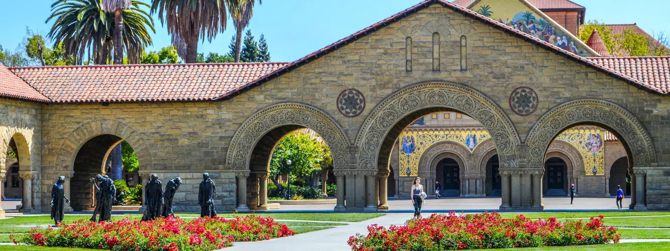 A landscaped courtyard shows a pathway leading past bronze statues to the center of a mission-style courtyard.