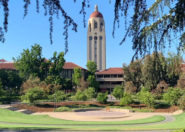 A bowl-shaped open space with lawn, trees, and a stage area, with Hoover Tower rising in the background.