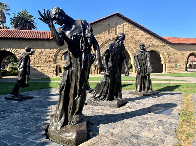 Bronze casts representing Rodin's "Burghers of Calais" stand on a cobblestone plinth in Memorial Court.