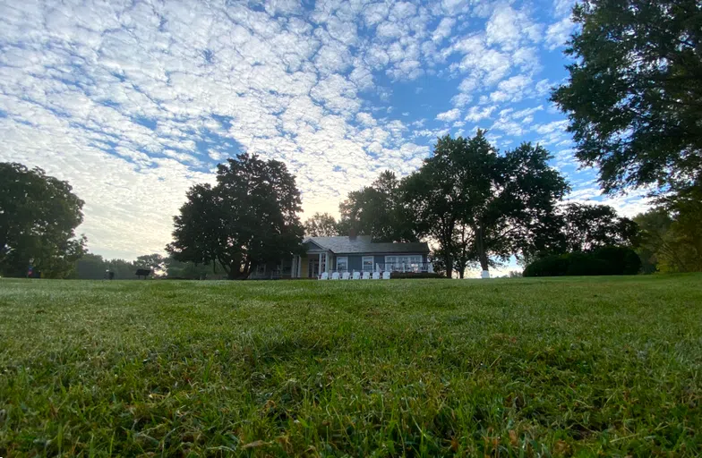 A view of the Admission Welcome Center from Admissions front lawn. The sun is rising behind the building.