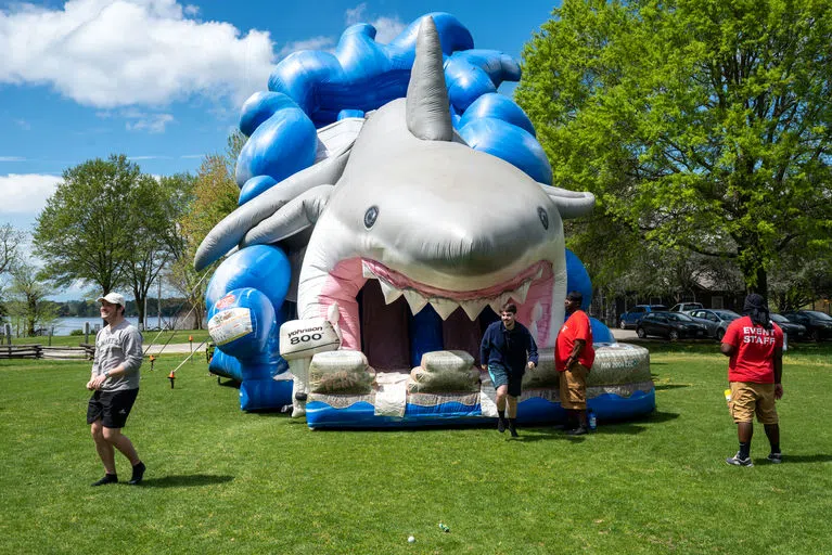 Students riding on a giant inflatable shark on Admission's field