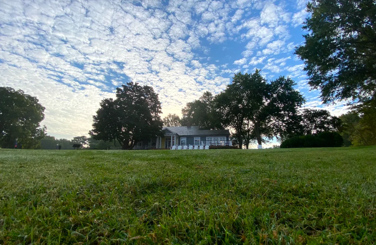 A view of the Admission Welcome Center from Admissions front lawn. The sun is rising behind the building.