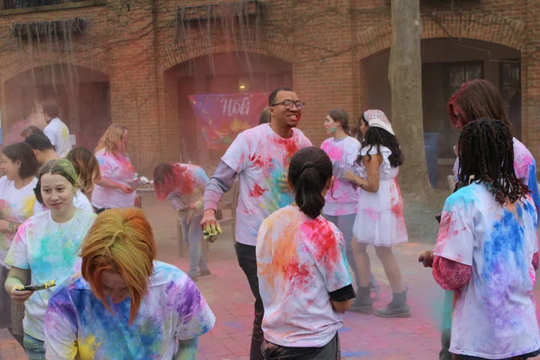 Students participating in a color throw during a Holi celebration.