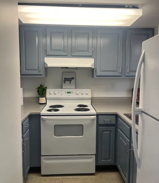 Updated townhouse kitchen with upper and lower cabinets and white, full size appliances