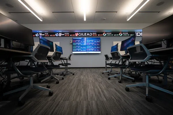 Finance Lab in Bastin Hall. Image of chairs at different desk stations with stock ticker around the room's walls. 