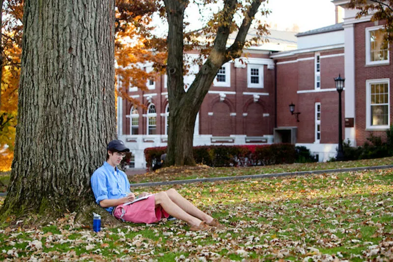 A student relaxes on the Academic Quad near Eaton Hall