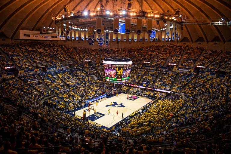 Stadium seating filled with fans surrounds the basketball court.