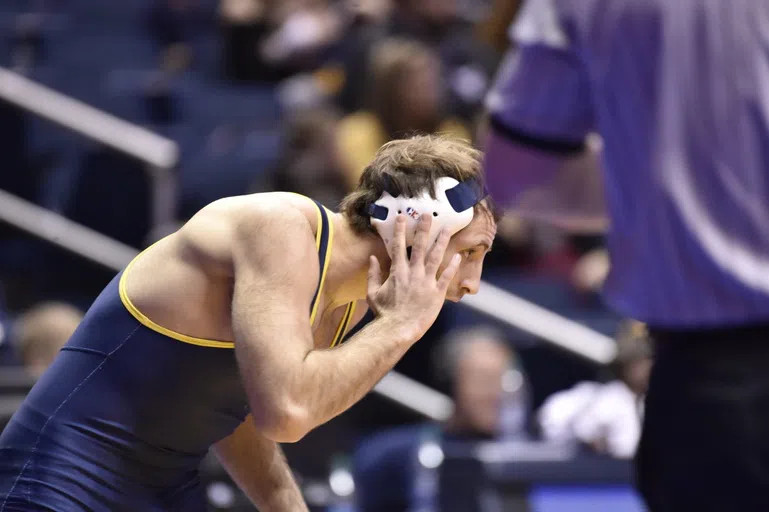 A wrestler touches his headgear.