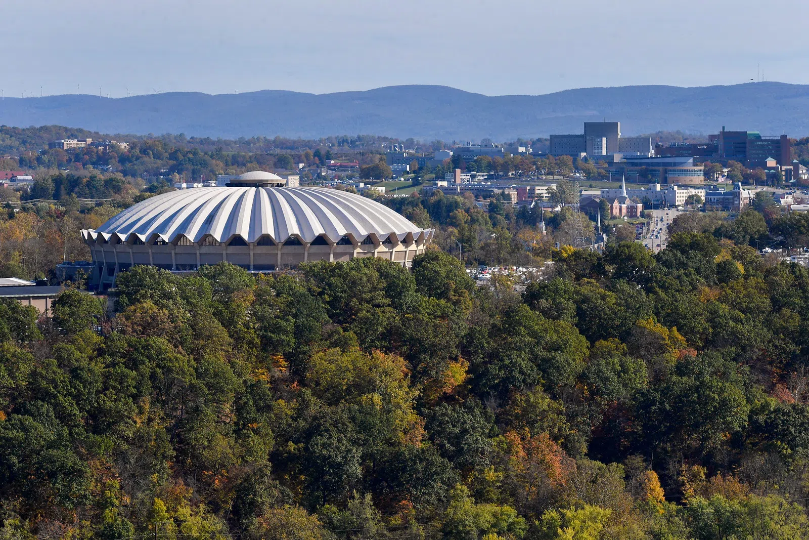 Image shows a wide shot of the Coliseum exterior against Morgantown foliage. 