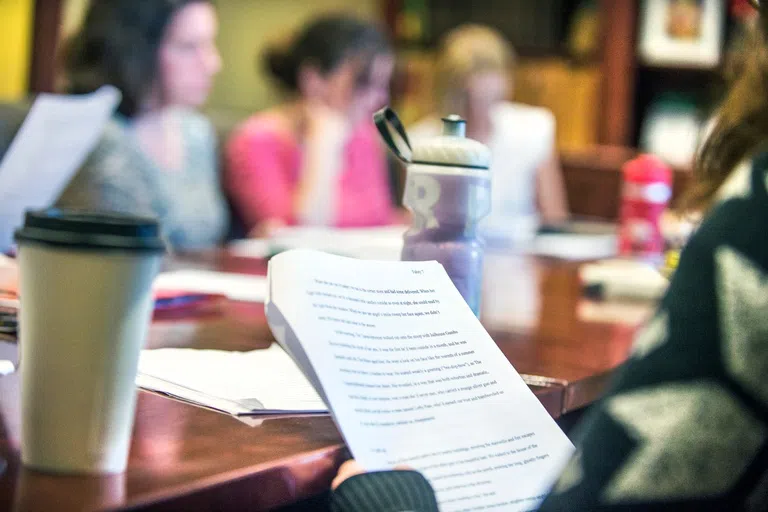 A photo of students sitting at a table with the focus on a report. 