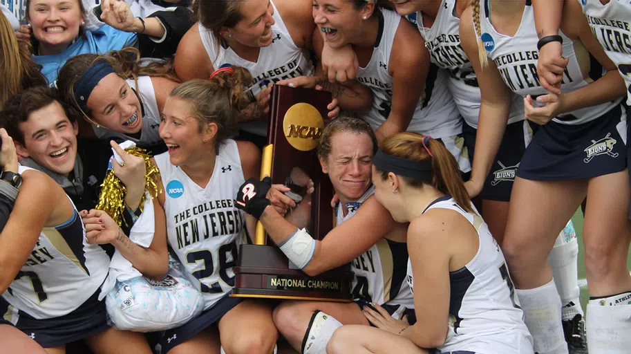 Lacrosse team hugging trophy