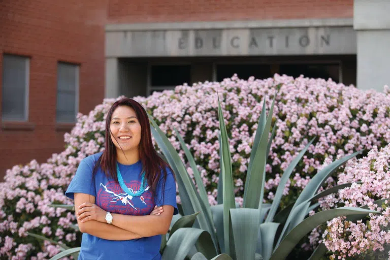 Indigenous student standing in front of Education building