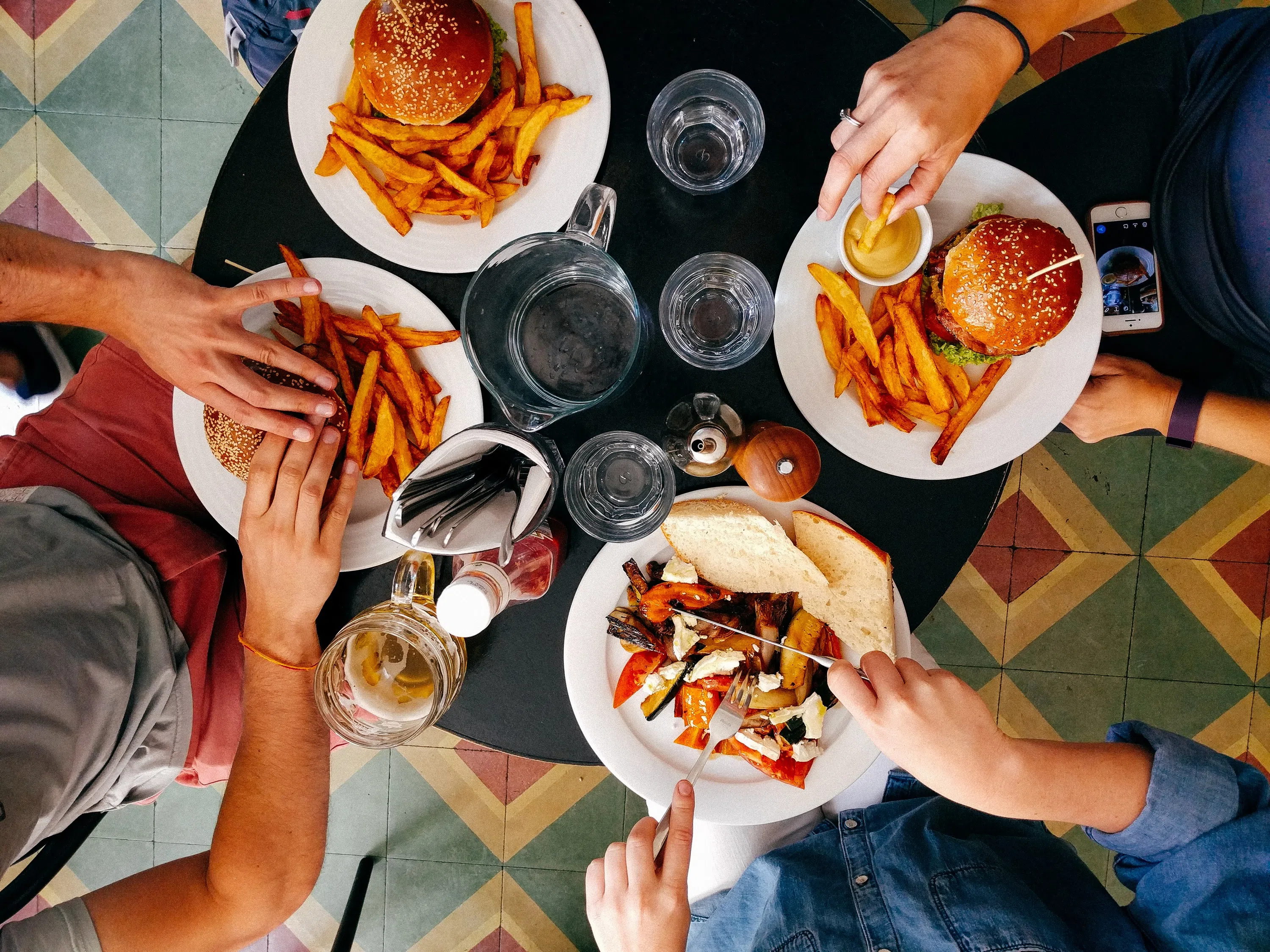 Students each with a plate of food - cheeseburgers, fries, vegetables. Water on the table. 