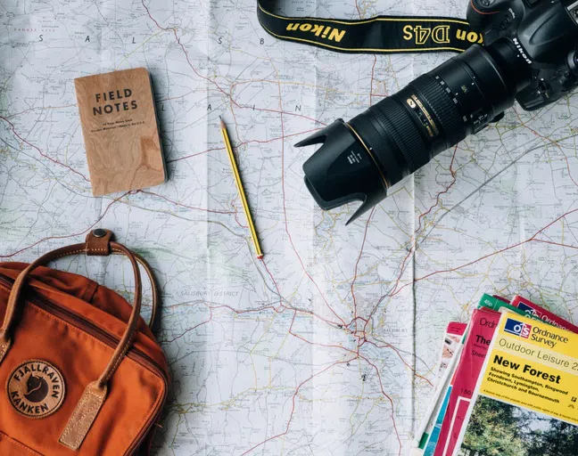 Map, camera, backpack and pencil for a trip