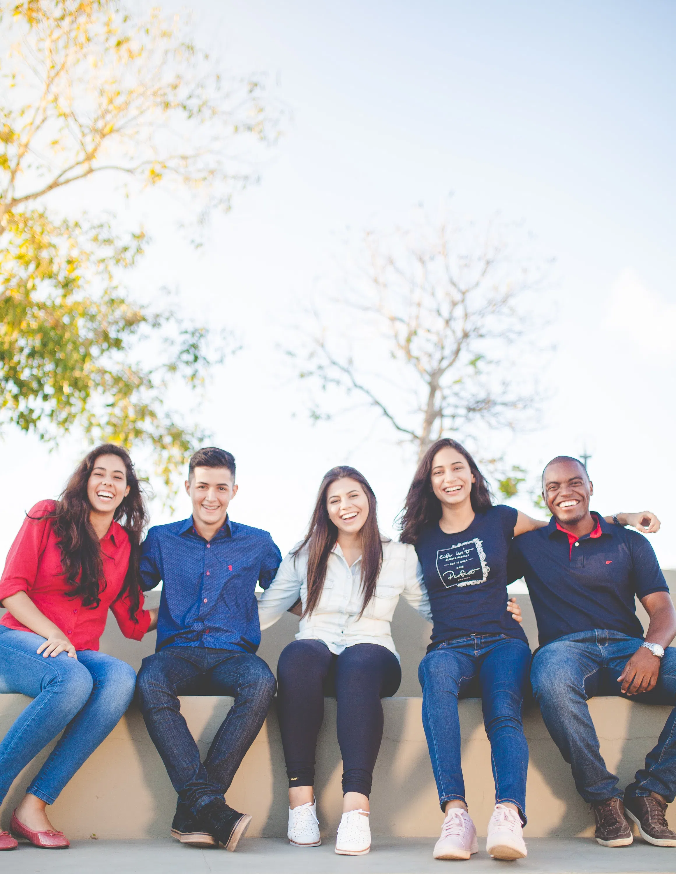 Group of young people sitting on a half wall outside