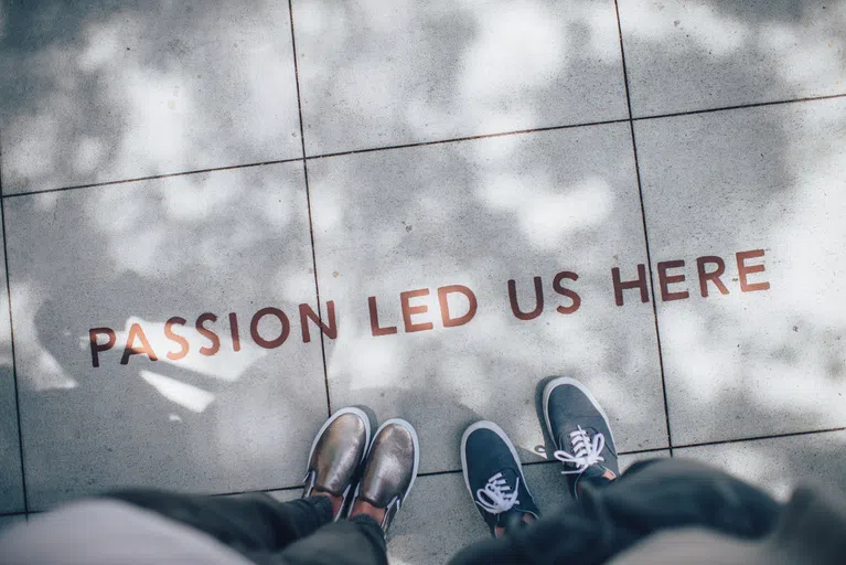 Shoes with the words "Passion Led Us Here" written on the sidewalk