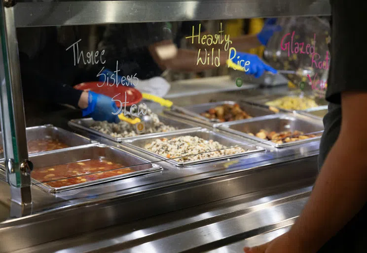 A close up picture of the food options, with an employee scooping food onto a student's plate. 