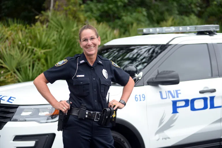 Police Officer poses in front of police car