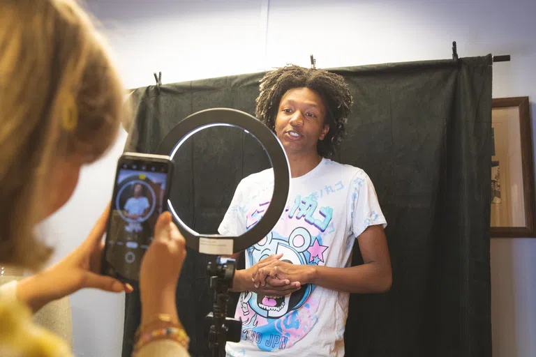 Two students using equipment and backdrop in the Social Media Lab in building 36.