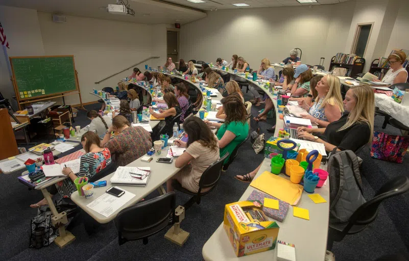 Education students in a theater style classroom working with a variety of supplies to create curriculum for classrooms