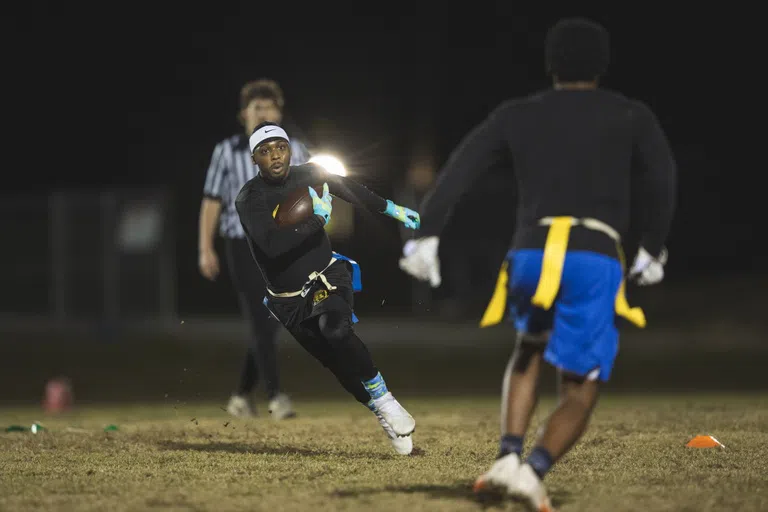 Two students and a referee in a flag football game. 