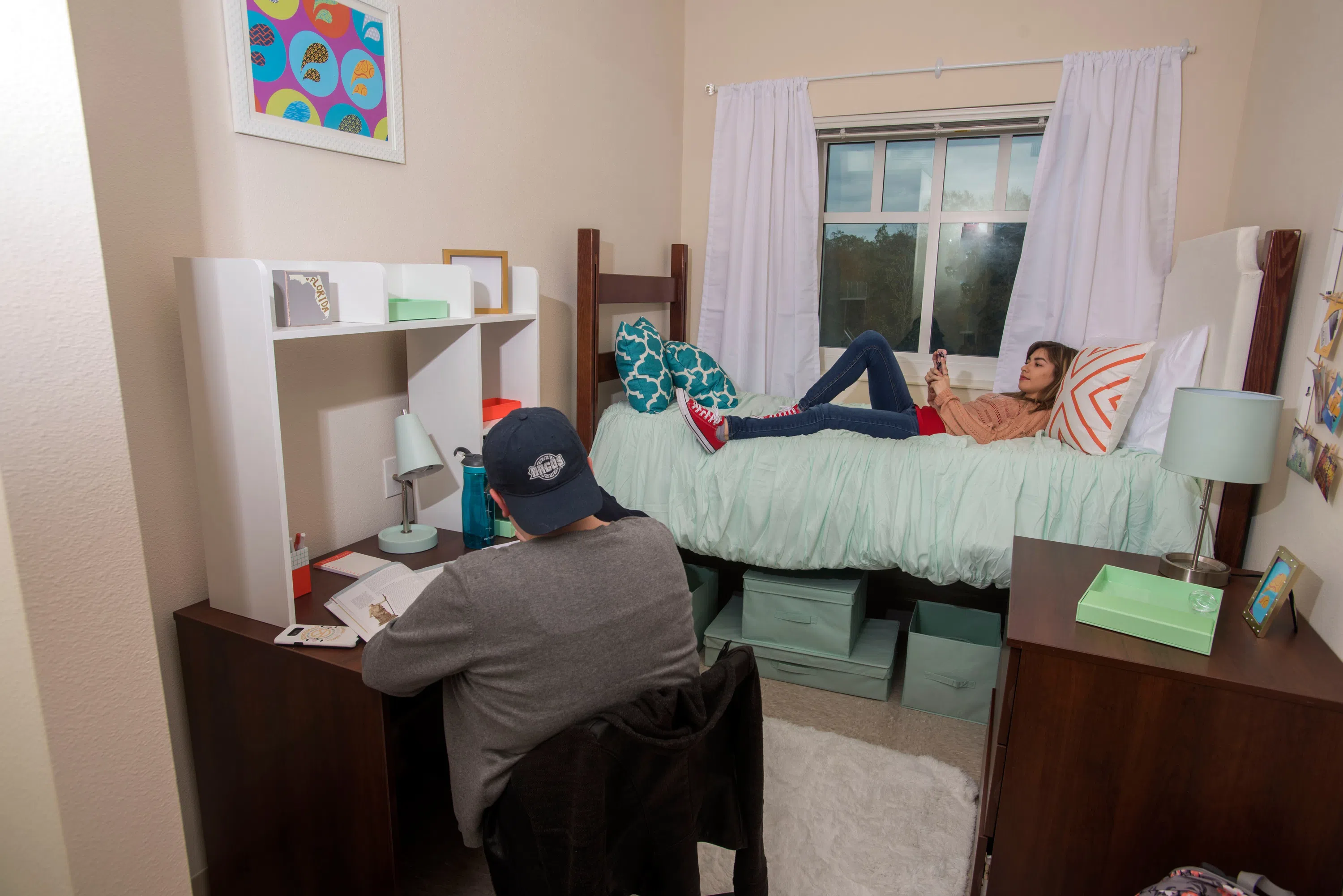 Women studying in a single bedroom with a raised bed