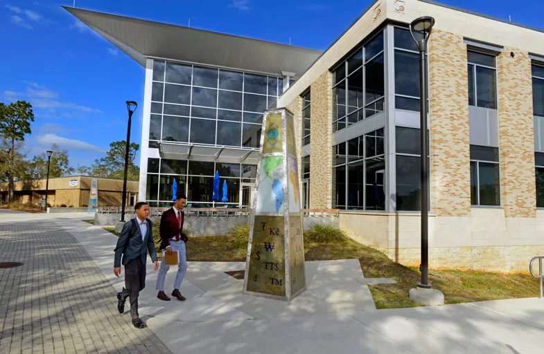 Two students in suits walking past the College of Business.