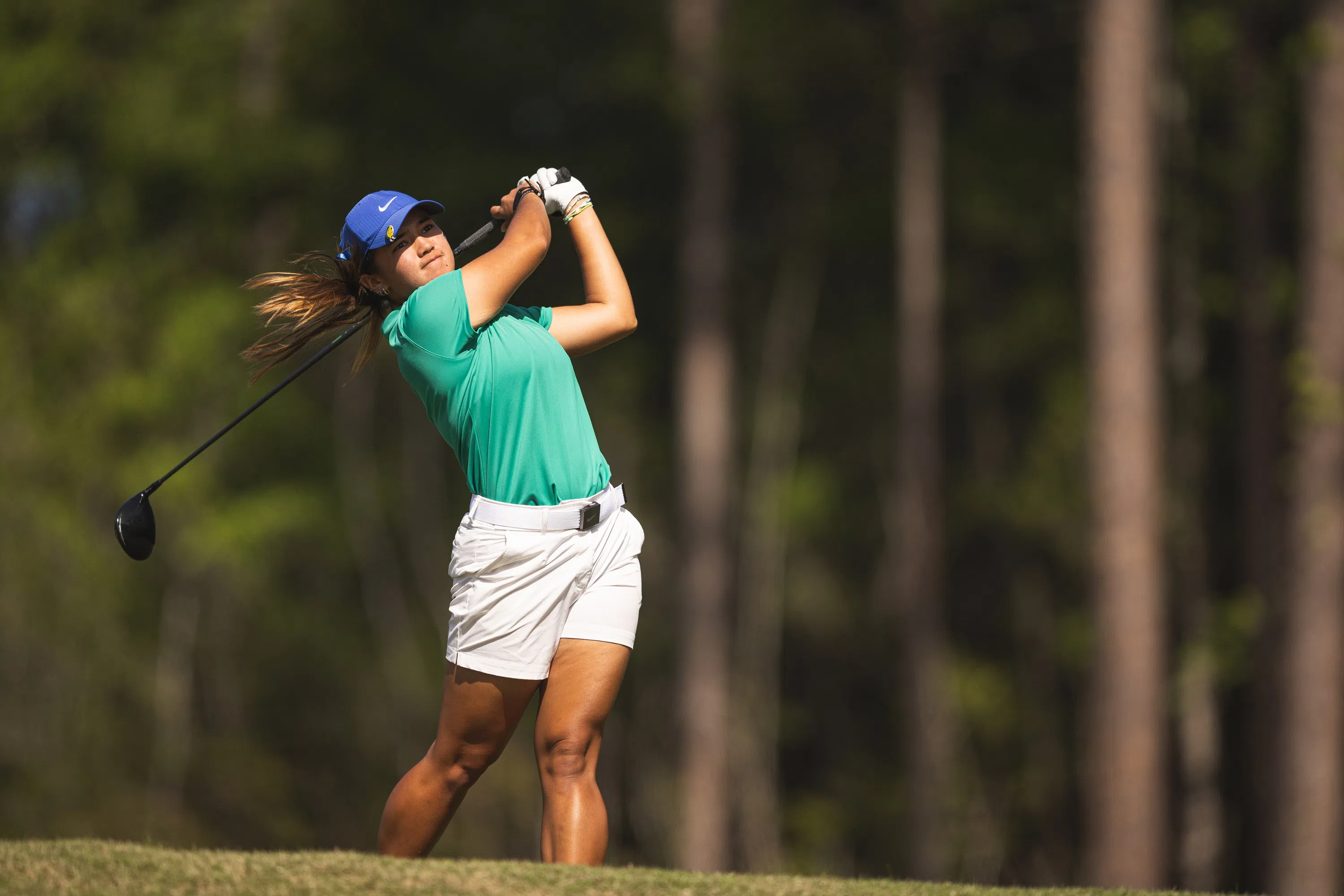 Women's golf player tees off.