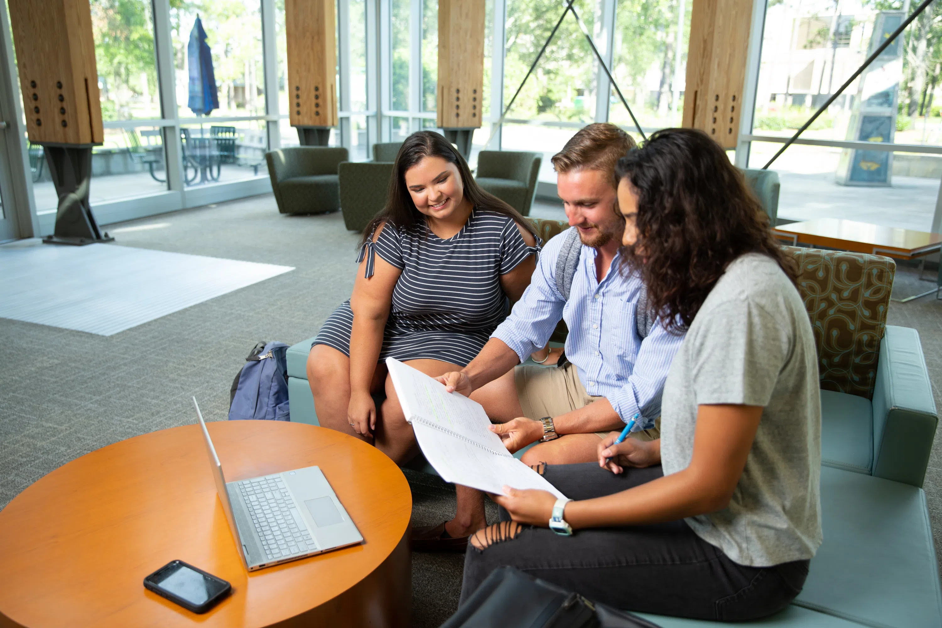 Three students meeting in the College of Business Atrium. 