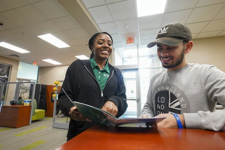 Housing staff looking at a housing brochure with a student.