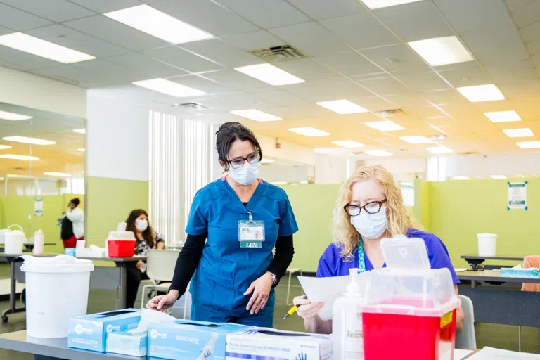 Focus on two female health professionals in scrubs reviewing paperwork.